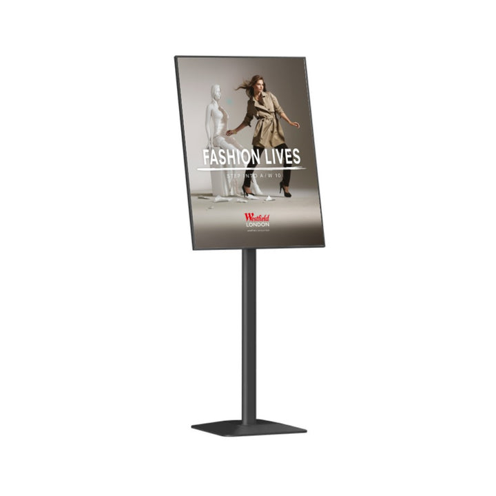 Photographed at an angle, the satin black stand carries its A3 frame on a single upright above a square weighted base, sized for lobby and foyer signage.
