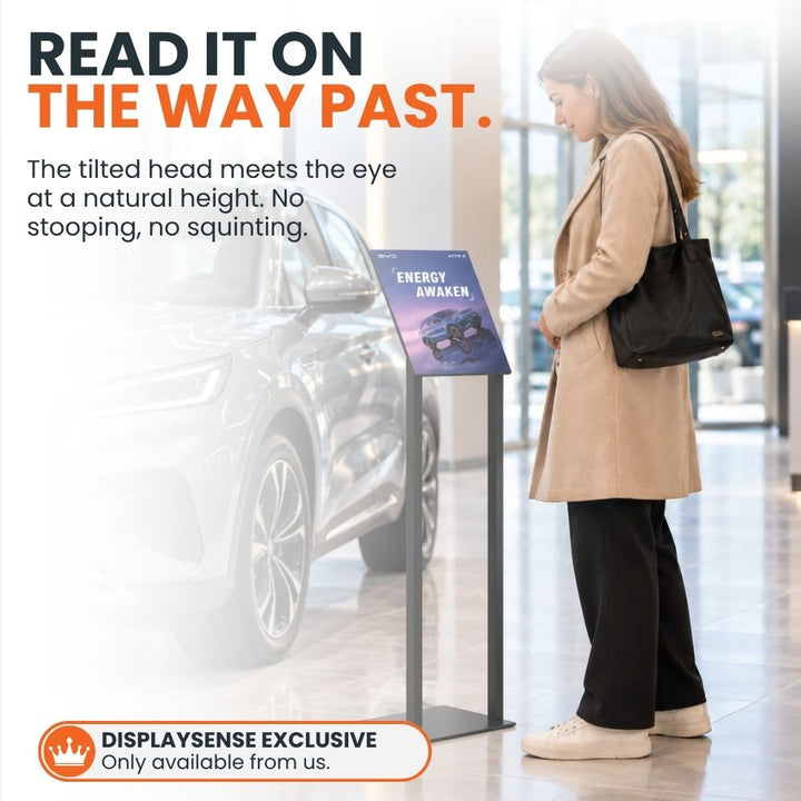 Customer reading the angled A4 poster stand beside a vehicle in a showroom, illustrating its convenient viewing position for passing visitors.
