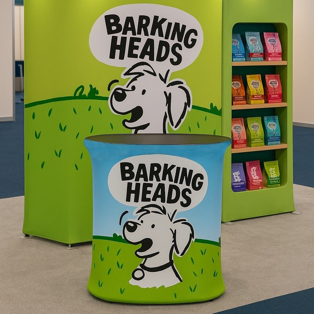 Barking Heads promotional counter with cartoon dog branding at a green and blue themed exhibition stand.

