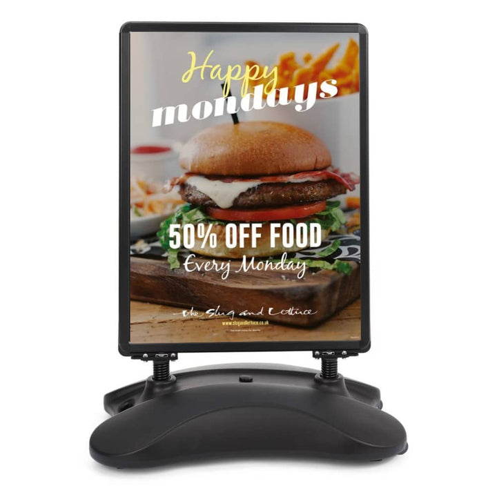 Black A1 waterbase pavement sign cut-out showing the curved 25-litre water-fillable base, spring-mounted frame and double-sided snap-frame panel.
