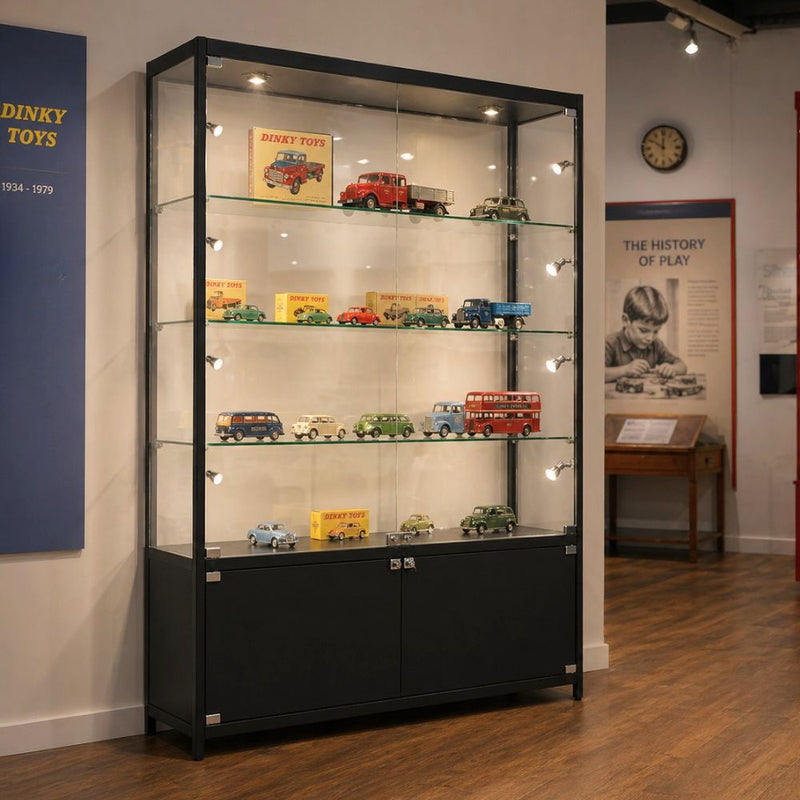 Black aluminium lockable glass display cabinet with adjustable shelves and LED lighting showcasing model vehicles in a museum-style setting.