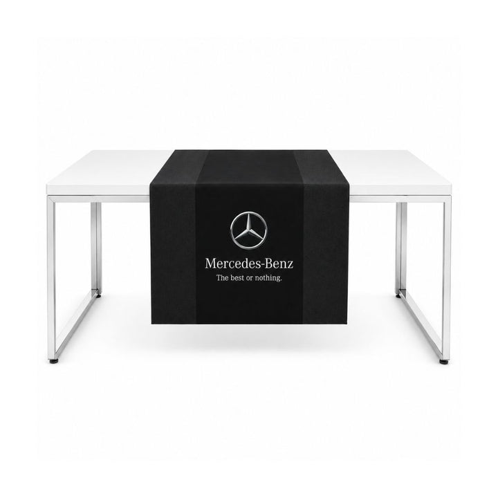 Black branded table runner with Mercedes-Benz logo displayed across a white exhibition table on a plain background.
