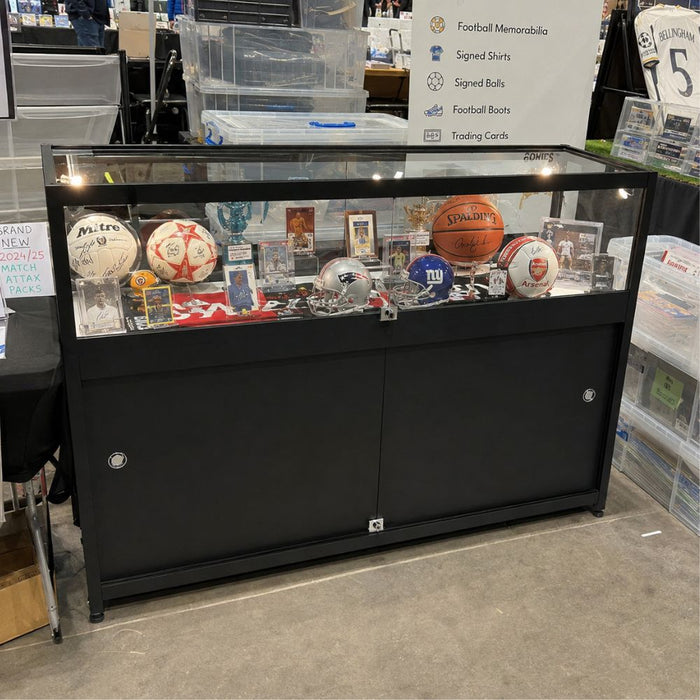 Black counter sports memorabilia display cabinet with signed balls and trading cards