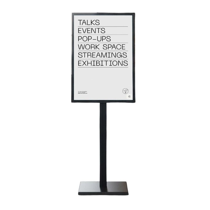 Black double-sided A1 poster stand on a heavy weighted circular steel base, shown on a white background with an event information poster loaded.
