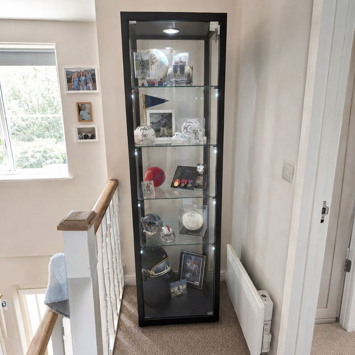 Black illuminated glass sports memorabilia display cabinet on a landing