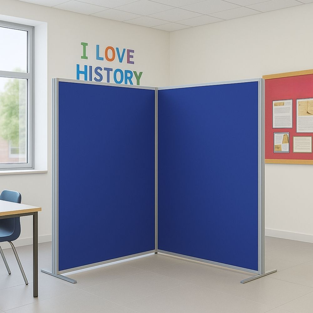Two-panel blue fabric divider with silver frame and flat feet, positioned in a school classroom corner near a window, wall display board, and colourful "I Love History" wall lettering.