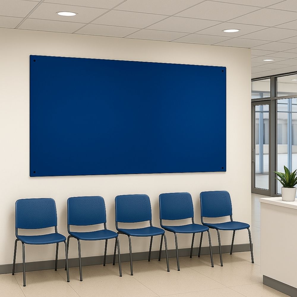 Dark blue fabric noticeboard fixed to a white wall above a row of five matching blue chairs in a clean, modern office waiting room with tiled flooring and a reception counter.