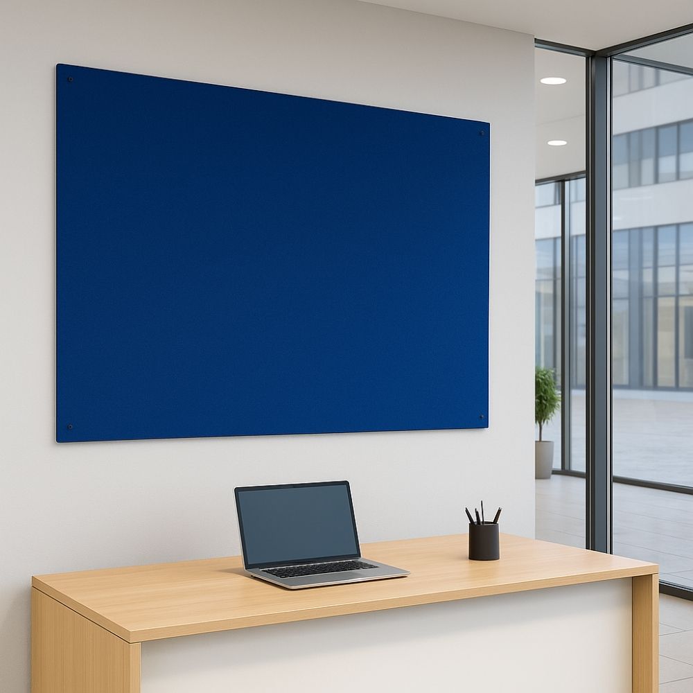 Royal blue fabric noticeboard affixed to a white wall above a minimalist wooden desk with a laptop and pen holder in a sleek modern office with floor-to-ceiling windows.