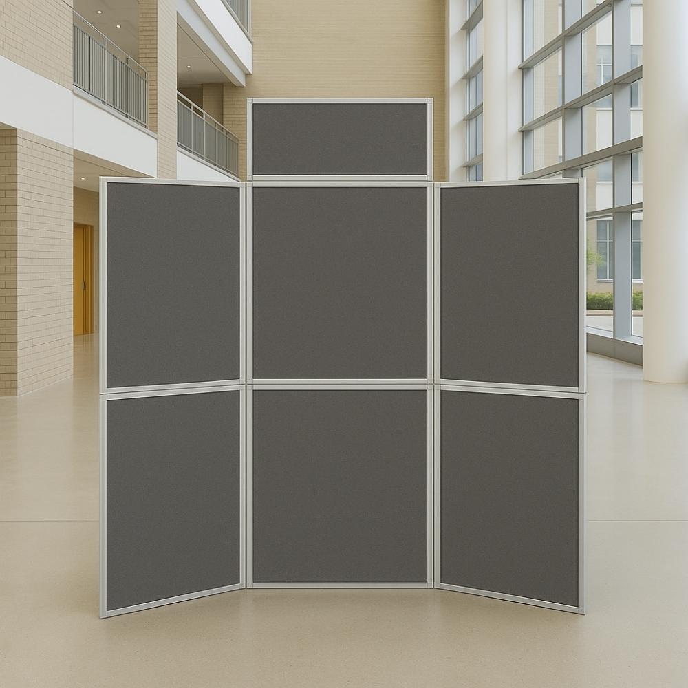 Freestanding grey six-panel folding display board with silver frame, set up in a spacious modern atrium with large windows and neutral décor.