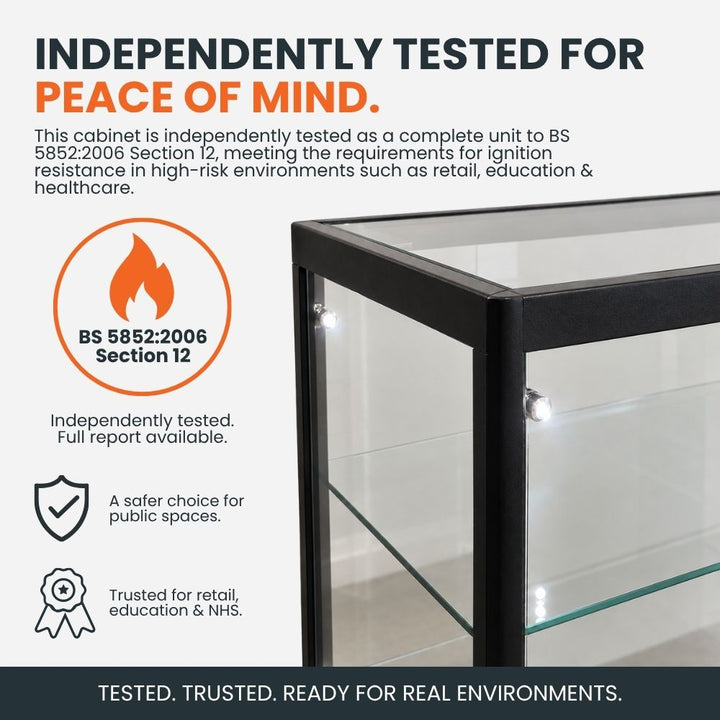 Black aluminium glass counter display cabinet highlighting independent BS 5852:2006 Section 12 ignition resistance testing for retail, education and healthcare environments.