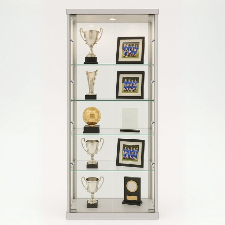 Silver glass display cabinet showing trophies, team photographs and awards across four illuminated shelves in a school or club environment.
