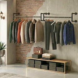 Industrial style wall-mounted clothes rail displaying garments on hangers with shelving and storage boxes in a modern retail interior.