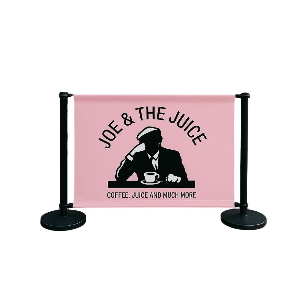 Studio image of Joe & The Juice café barrier featuring pink banner with black silhouette logo and matte black stanchions—designed for hospitality and coffee shop exteriors.

