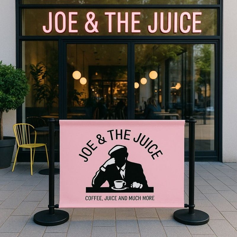 Pink branded café barrier with Joe & The Juice logo in use outside café entrance—ideal for enhancing brand visibility and creating stylish outdoor seating areas.

