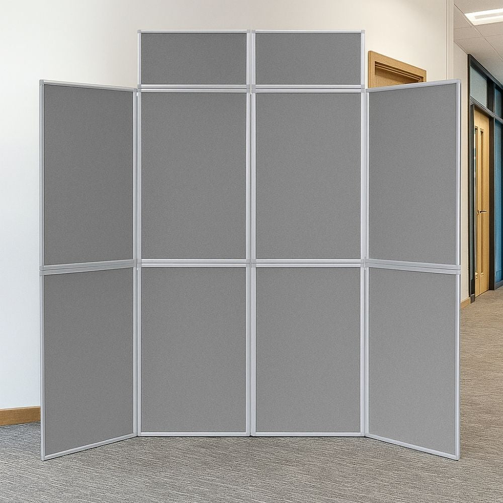 Freestanding light grey eight-panel folding display board with silver frame, positioned in an office hallway with grey carpet and wooden doors.

