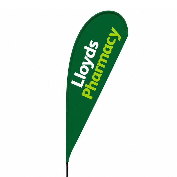 Lloyds Pharmacy branded green teardrop flag displayed outside a UK pharmacy branch for roadside advertising and customer visibility.