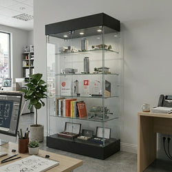 tall-glass-display-cabinet-in-contemporary-office-showcasing-awards-books-and-architectural-models-within-bright-workspace