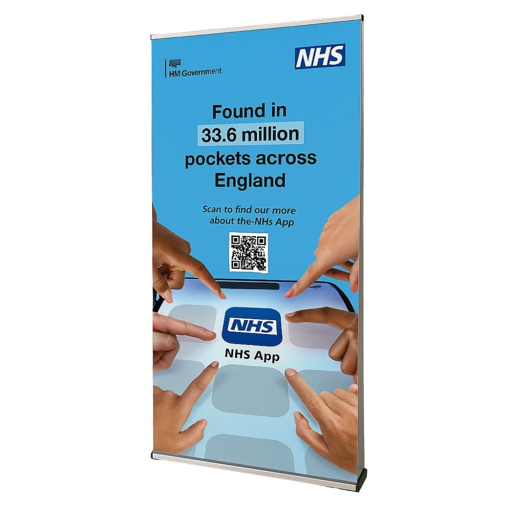 Close-up front view of a NHS App roller banner with vibrant blue background, hands pointing at the app icon and QR code included for download.