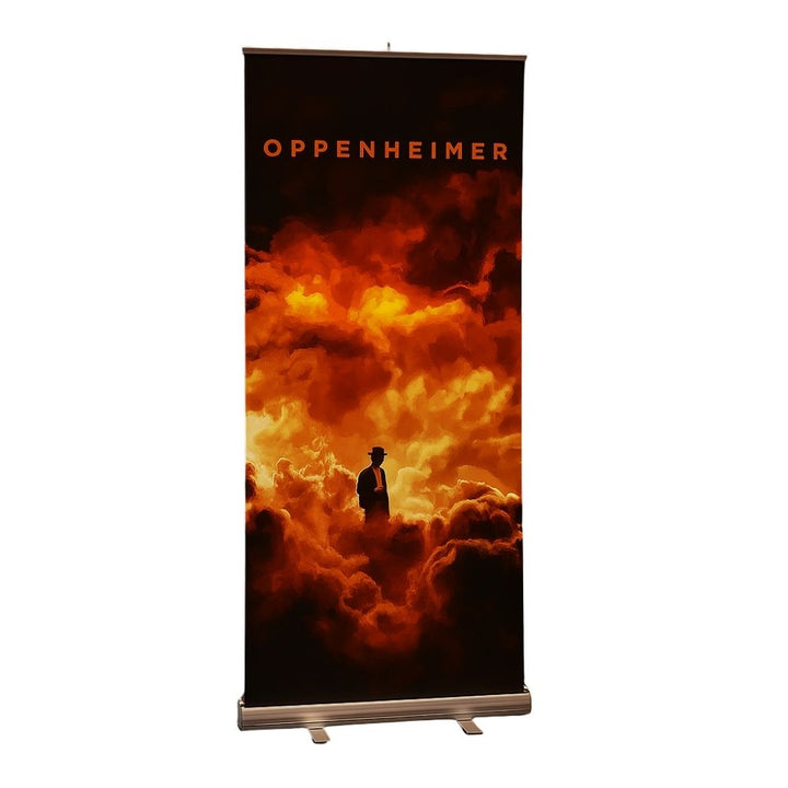 Side-angled product photo of an Oppenheimer 800mm roller banner with dramatic orange cloud artwork and silhouette figure, printed for high-impact visual display.

