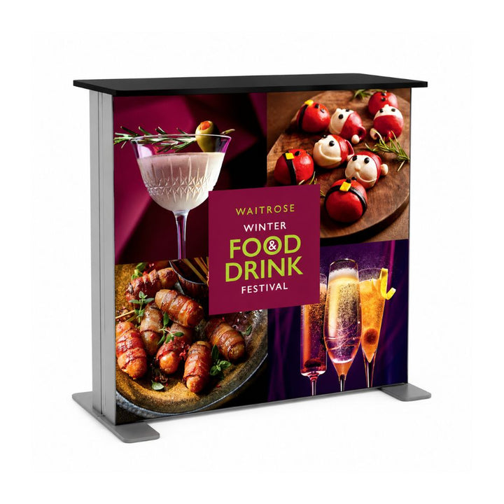 Portable promotional counter display featuring Waitrose winter food and drink festival graphics with cocktails, appetisers and champagne imagery.