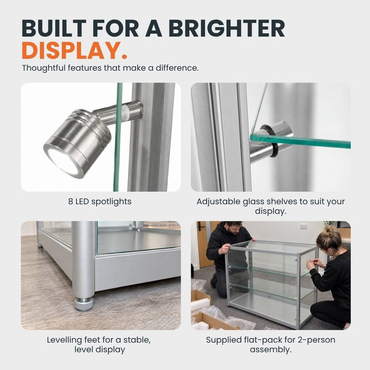 Silver glass counter display cabinet feature guide showing eight LED spotlights, adjustable glass shelves, levelling feet and flat-pack two-person assembly.
