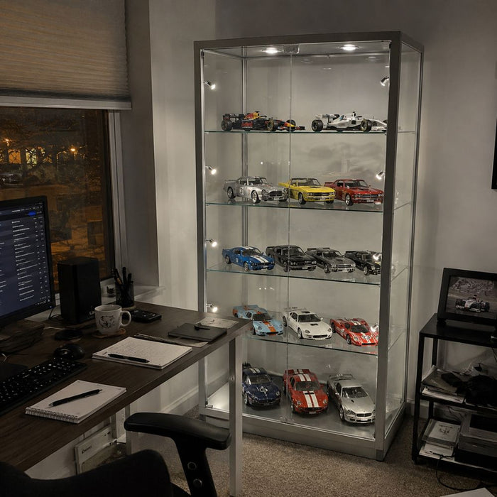 Silver glass display cabinet displaying a Formula 1 and Le Mans diecast model car collection