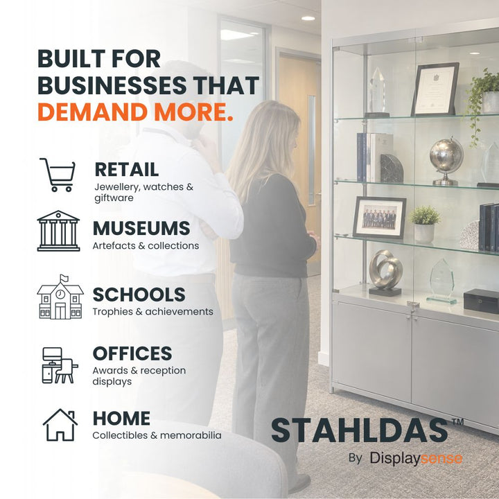 Silver glass display cabinet with adjustable shelves and lighting displaying awards, books and decorative pieces in a modern office reception.