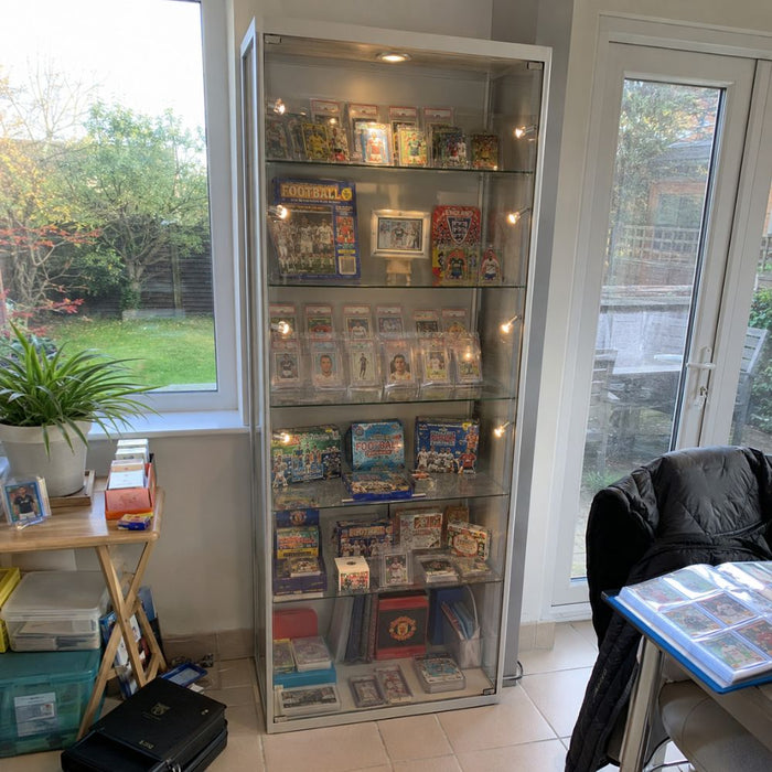 Silver glass football card display cabinet in a home collection room