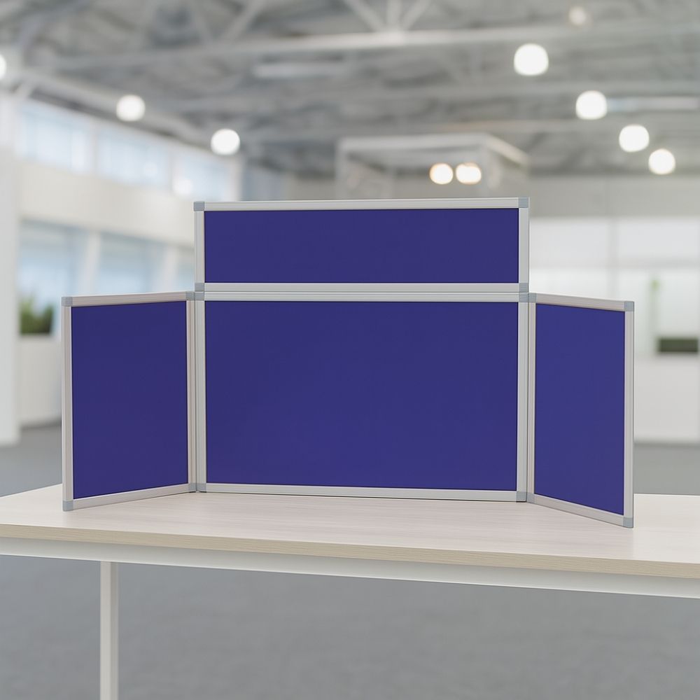 Compact tabletop display board with blue panels and silver frame, placed on a light wood table in a bright modern office or exhibition space.


