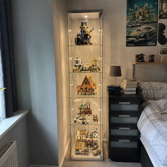 Tall lit glass display cabinet of an assorted LEGO collection