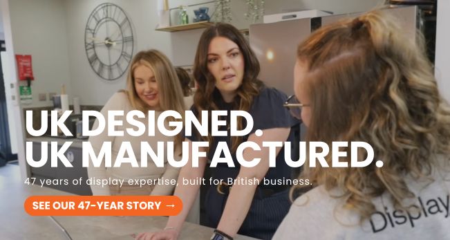 Team members discussing display solutions in a workplace setting, highlighting UK designed and UK manufactured products with over 47 years of display expertise.