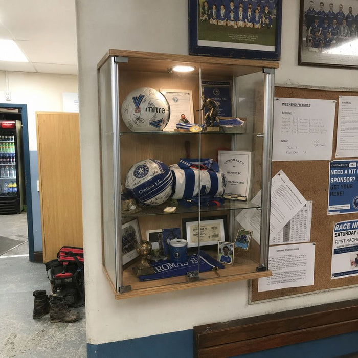 Wall-mounted wooden football memorabilia display cabinet in a clubhouse
