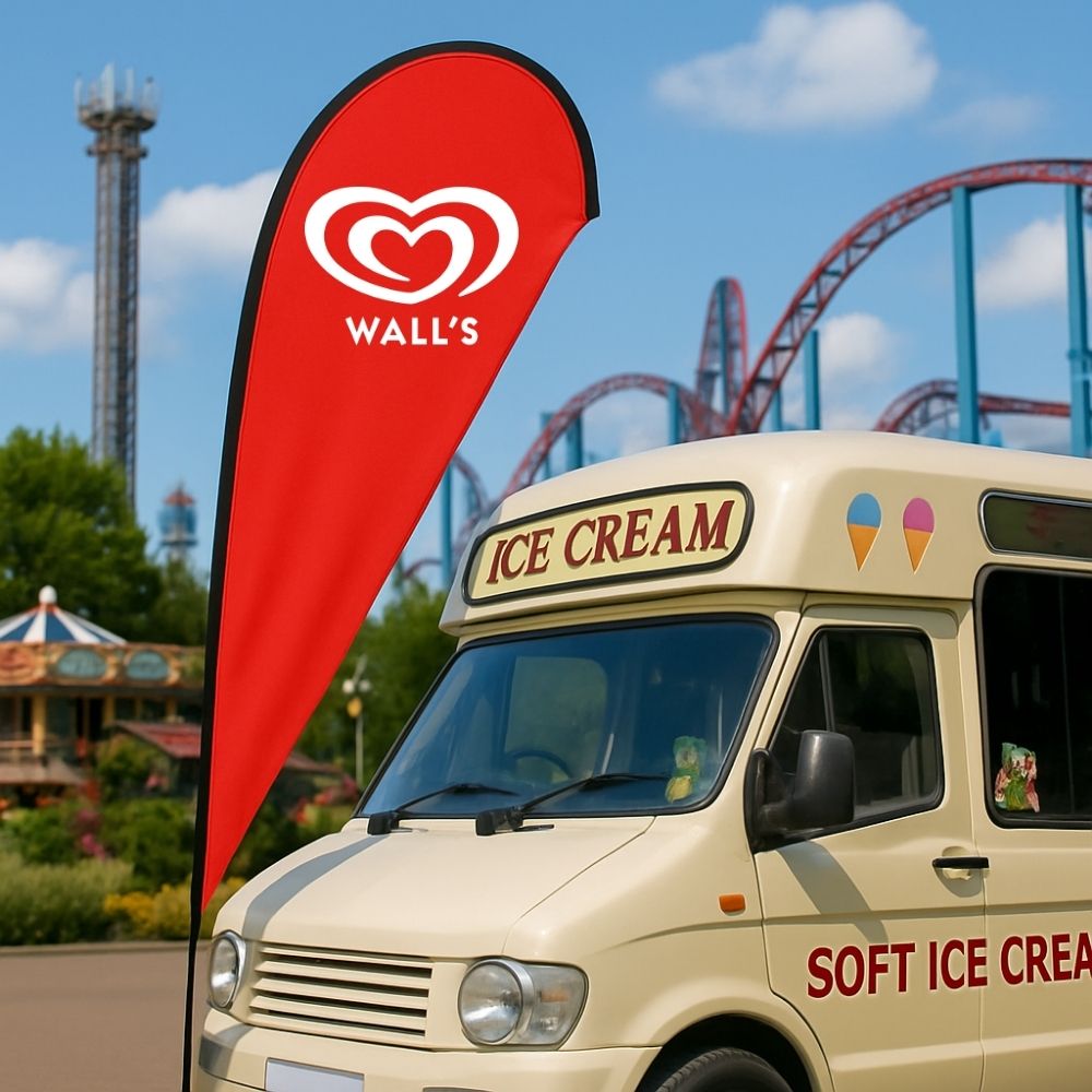 A single-sided teardrop flag standing beside an ice cream van at a theme park