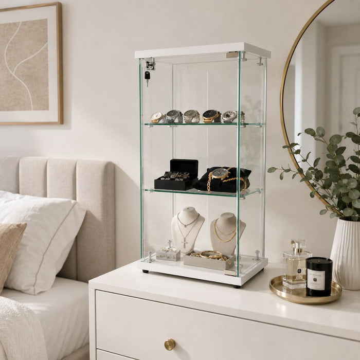 White glass jewellery display cabinet on a bedroom dresser displaying rings, bracelets and sentimental jewellery