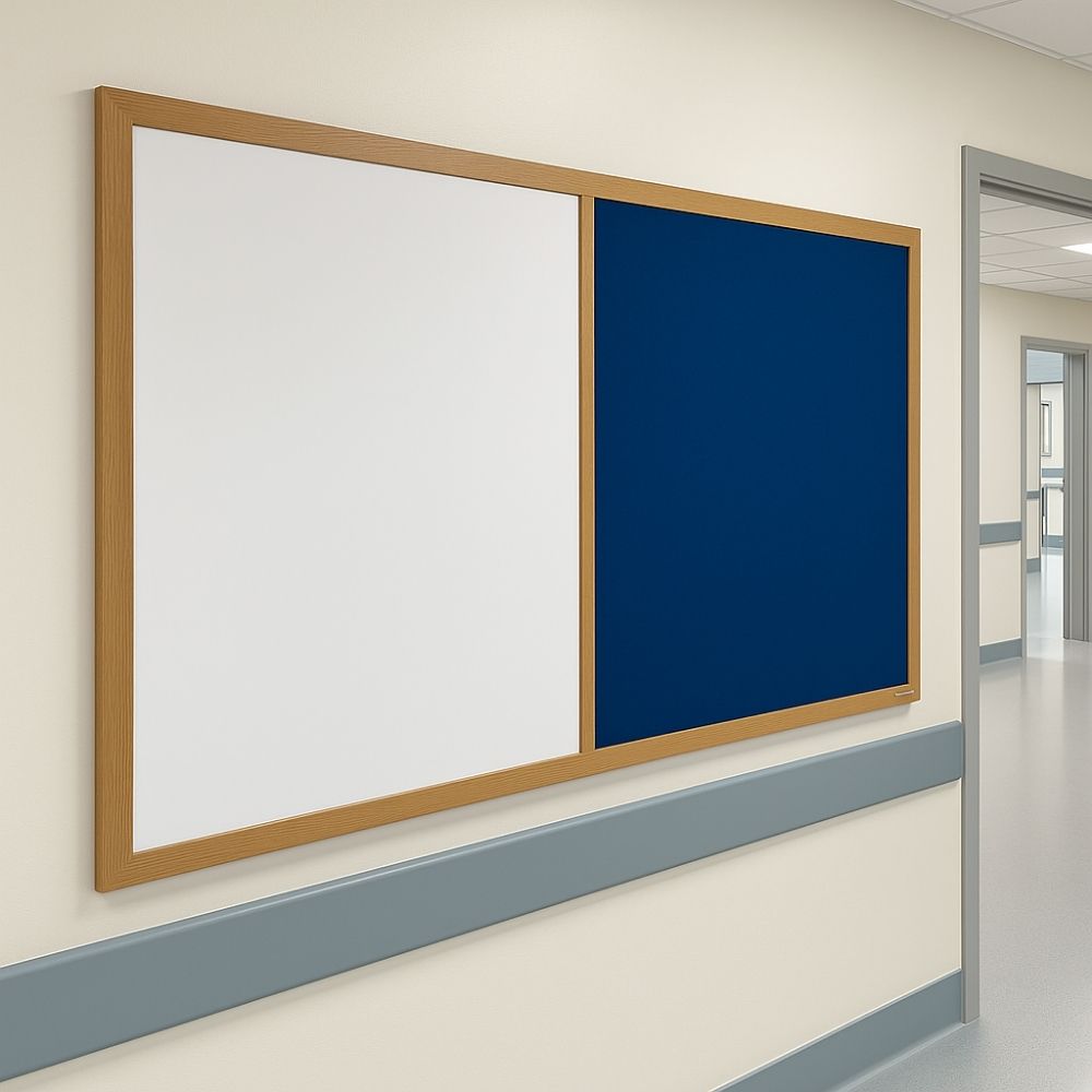 Wall-mounted 1800mm x 1200mm whiteboard and dark blue felt noticeboard combination with a wooden frame, installed in a clean, modern hospital corridor with cream walls and grey dado rails.


