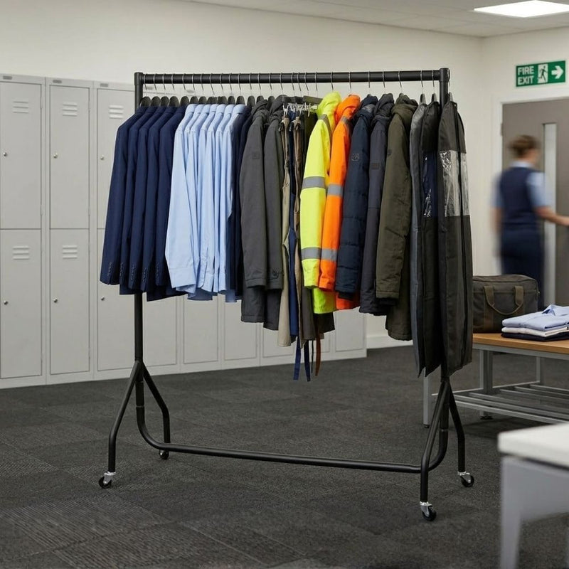 Black 4ft clothes rail on castors in a workplace changing room storing suits, shirts, hi-vis jackets and outerwear beside staff lockers.

